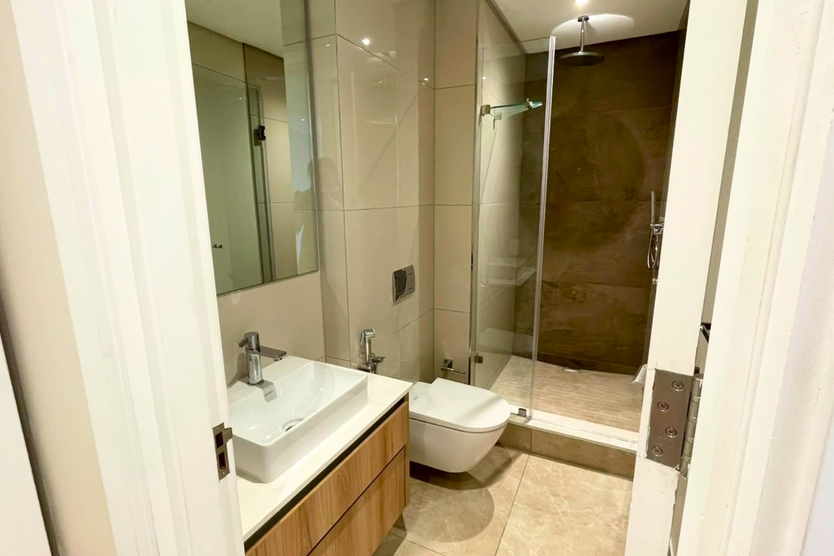 Modern bathroom featuring a wall-mounted toilet, glass-enclosed shower with rain head, and a contemporary vanity with a vessel sink.
