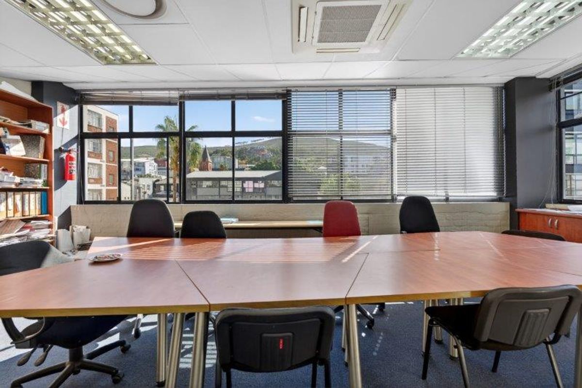A functional office space featuring a suspended ceiling, integrated air conditioning, and large windows providing natural light and urban views.