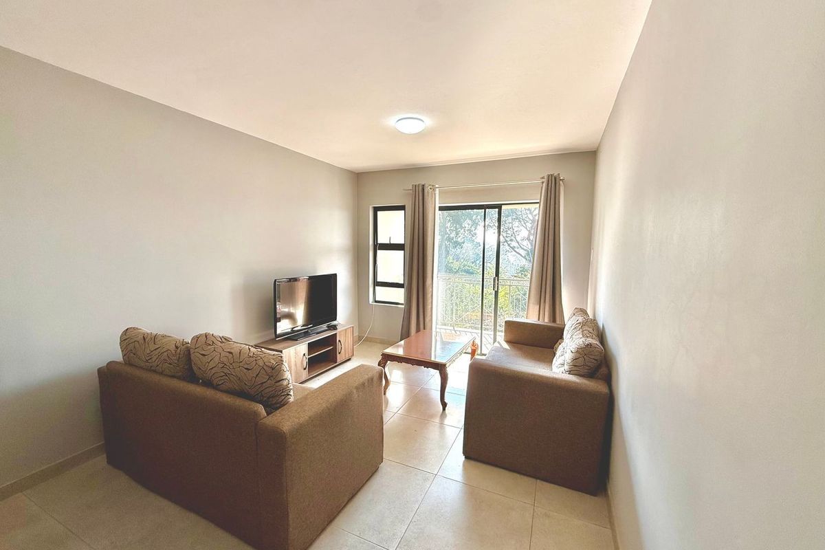 A bright living room featuring tiled flooring and sliding glass doors that open onto a balcony, providing natural light and outdoor access.