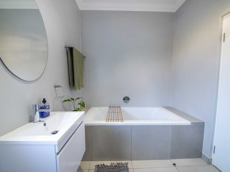 Modern bathroom featuring a built-in bathtub, sleek vanity cabinet with basin, and contemporary wall-mounted mirror.