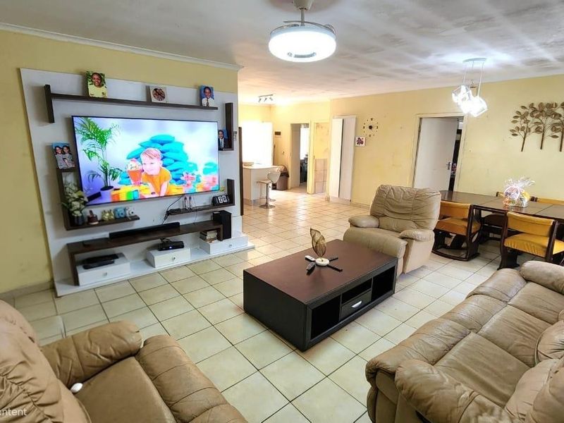 Open-plan living and dining area featuring ceramic floor tiles, a built-in media unit, and neutral wall finishes.