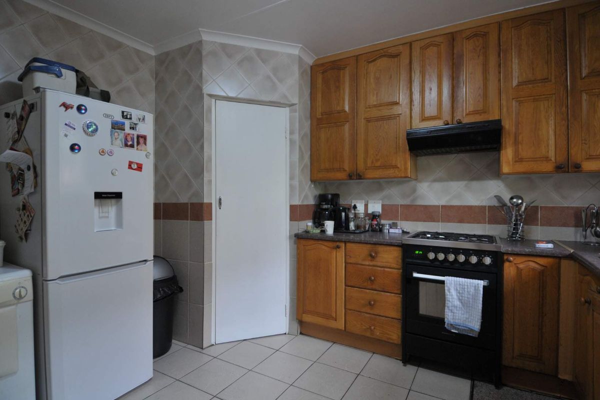 A functional kitchen featuring traditional timber cabinetry, tiled splashbacks, and a built-in gas oven and hob with an extractor fan.