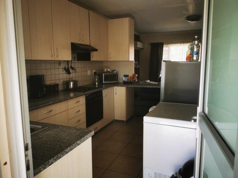 Functional kitchen featuring laminate cabinetry, granite countertops, tiled backsplash, and built-in oven with extractor fan, finished with durable ceramic floor tiles.
