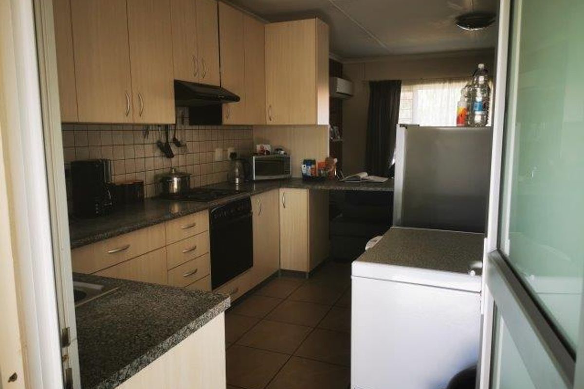 Functional kitchen featuring laminate cabinetry, granite countertops, tiled backsplash, and built-in oven with extractor fan, finished with durable ceramic floor tiles.