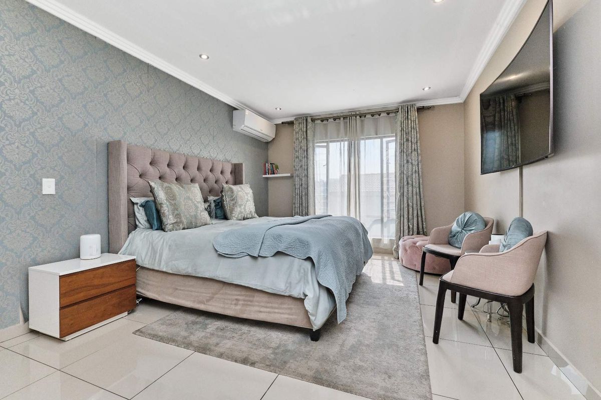 A well-maintained bedroom featuring tiled flooring, recessed downlighting, a split-system air conditioner, and direct access to an outdoor area via sliding glass doors.