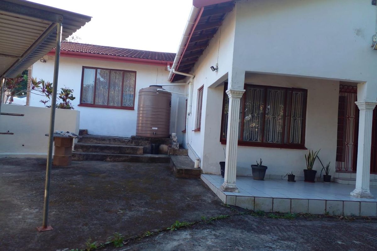 Rear exterior view of the property featuring a tiled patio, concrete paved area, and a water tank installation.