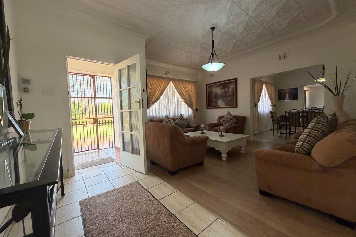 Spacious living area featuring a unique pressed metal ceiling, tiled and laminate flooring, and direct access to the exterior through a security gate.