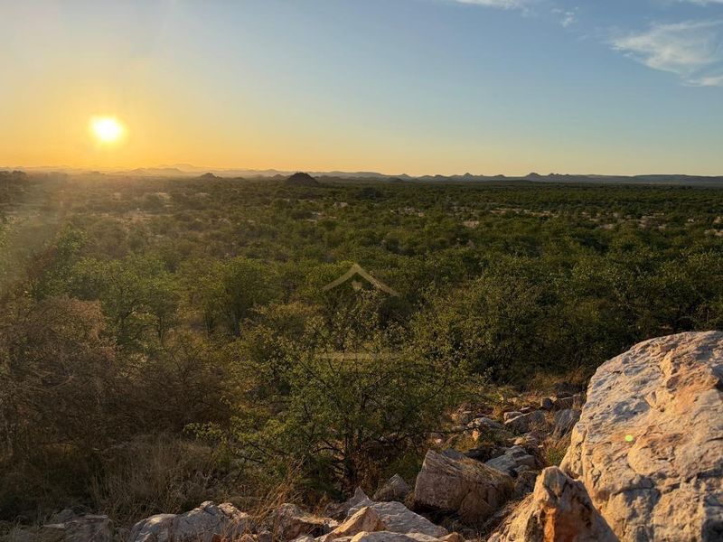 A scenic sunset view overlooking the expansive natural landscape and bushveld terrain of the farm property.