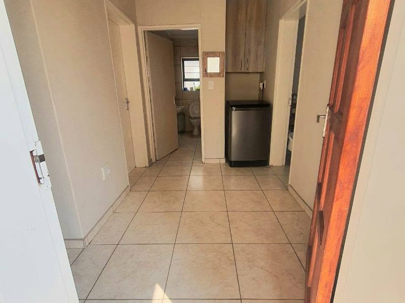A functional hallway featuring tiled flooring and built-in cabinetry, providing access to adjacent rooms including a bathroom.