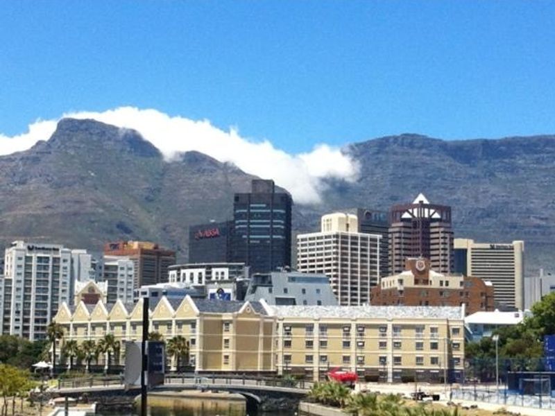 A scenic urban view featuring city skyline buildings set against a prominent mountain backdrop.