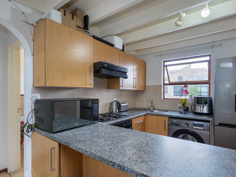Compact kitchen featuring laminate cabinetry, granite countertops, tiled backsplash, and exposed ceiling beams, providing a functional layout with integrated appliance space.