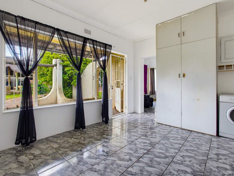 A functional laundry area featuring built-in storage cabinetry, tiled flooring, and direct access to the outdoor patio area.