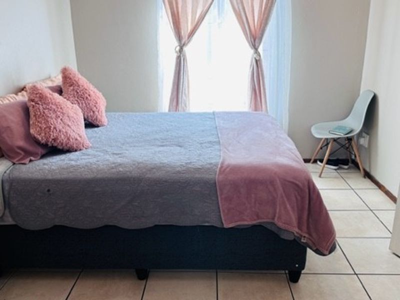 A functional bedroom featuring tiled flooring and a window, providing a neutral base for personalization.
