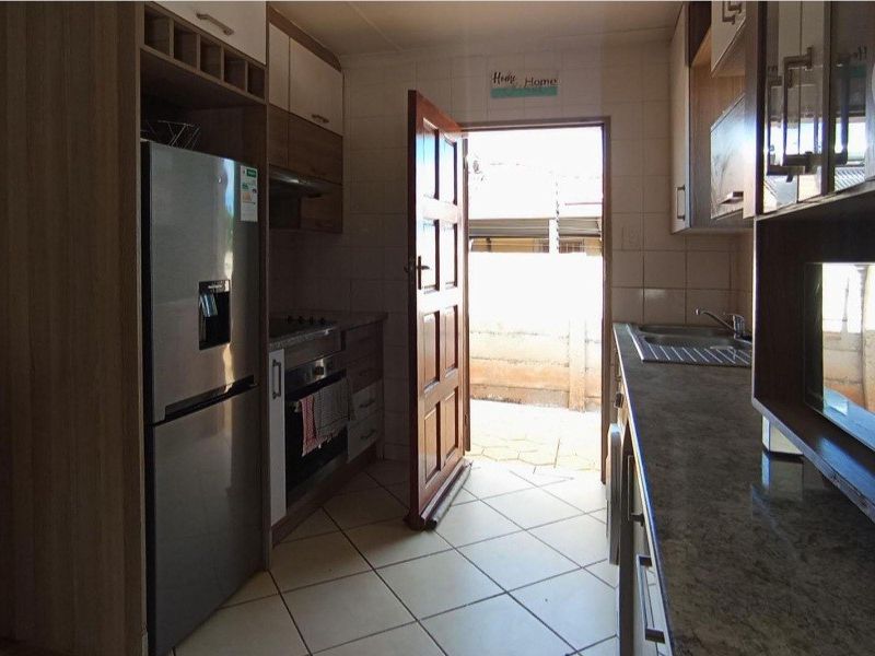 Functional kitchen featuring built-in cabinetry, stone countertops, integrated oven, and tiled flooring with direct access to the exterior.
