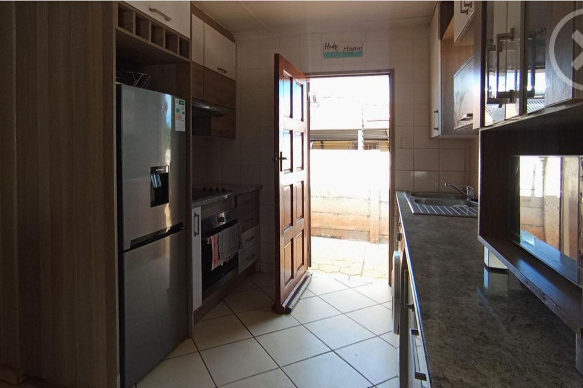 Functional kitchen featuring built-in cabinetry, stone countertops, integrated oven, and tiled flooring with direct access to the exterior.