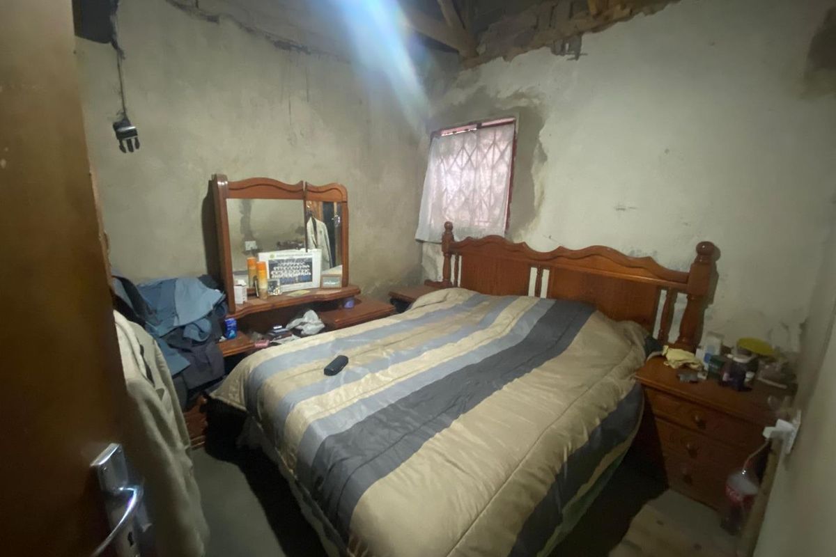 A bedroom featuring exposed roof rafters and unfinished wall surfaces, requiring significant renovation to complete the interior finishes.