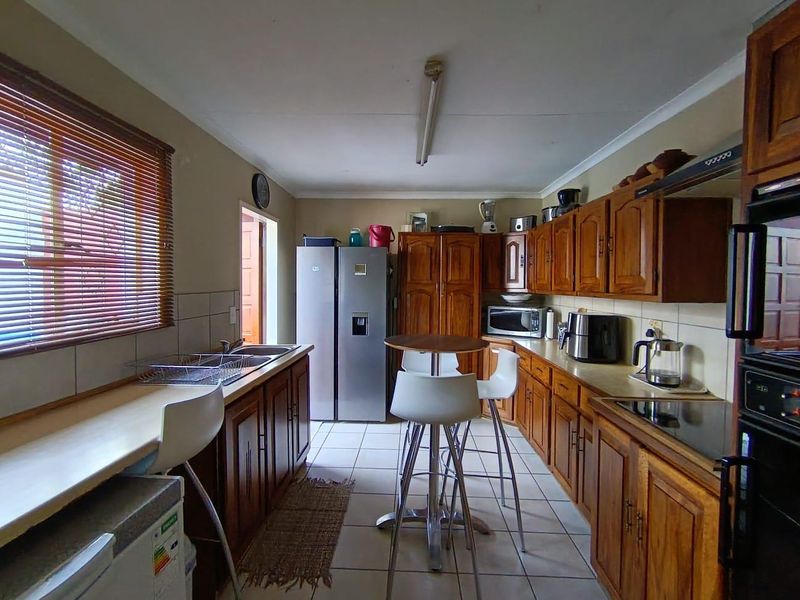 A functional kitchen featuring traditional wooden cabinetry, laminate countertops, a built-in oven, and tiled flooring, offering a classic layout with ample storage space.