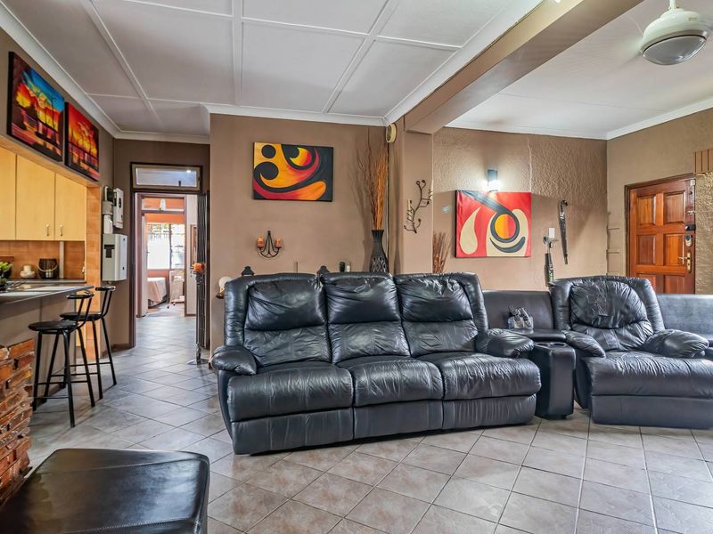 Open plan living area featuring tiled flooring, an exposed brick fireplace, and an integrated kitchen space with built-in cabinetry.