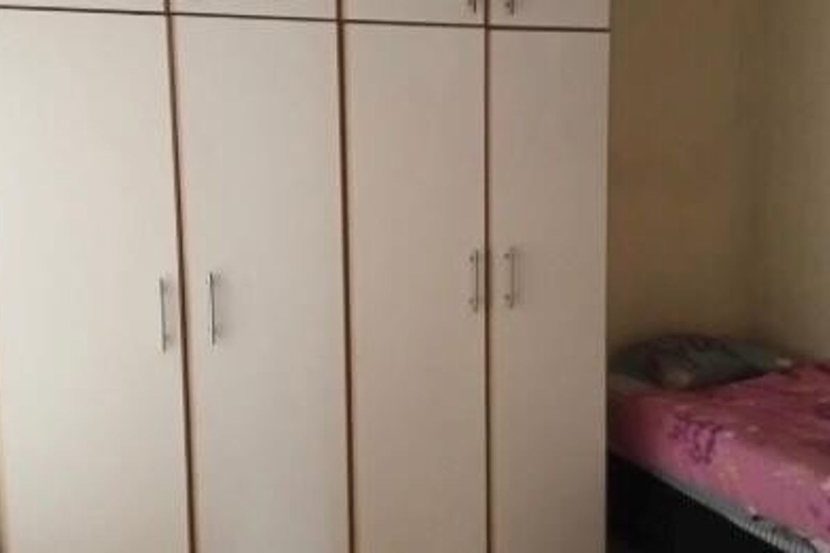 A bedroom featuring a large, light-colored built-in wardrobe with vertical handles.