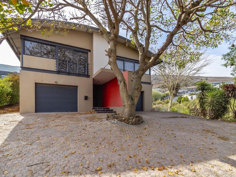 Modern two-story residential property featuring a paved driveway, double garage, and a distinctive red-accented entrance with an upper-level balcony.