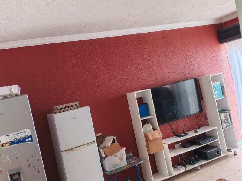 A living area featuring tiled flooring, a textured red accent wall, and ceiling cornice detailing.