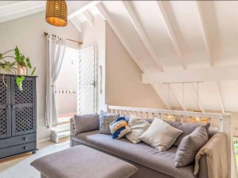 A bright living area featuring vaulted ceilings with exposed rafters, providing a spacious feel with direct access to an outdoor balcony.