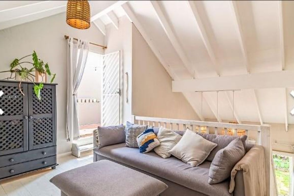 A bright living area featuring vaulted ceilings with exposed rafters, providing a spacious feel with direct access to an outdoor balcony.