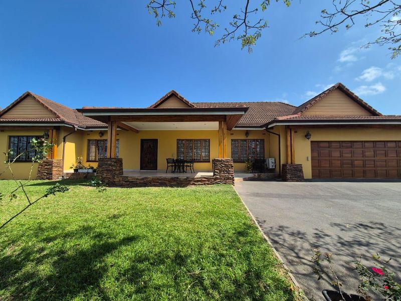 A well-maintained single-story residence featuring a covered patio, stone-clad pillars, timber-framed windows, and an integrated double garage with a paved driveway.