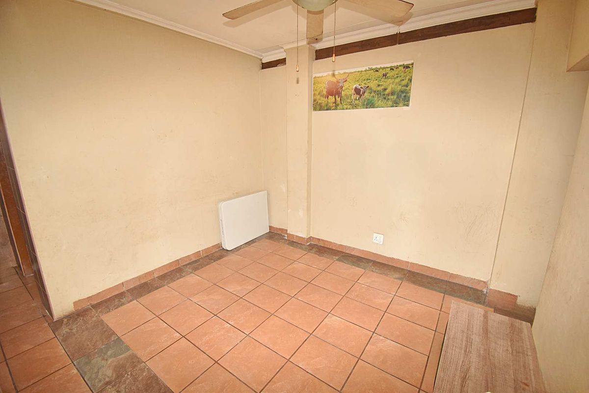 A small, empty room featuring tiled flooring, a ceiling fan, and plain walls, offering a blank canvas for potential renovation or restyling.