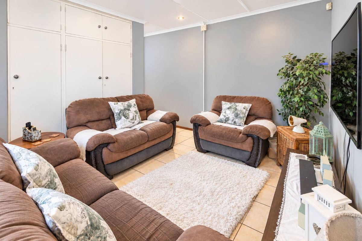 A comfortable living room featuring tiled flooring, built-in storage cupboards, and recessed ceiling lighting.