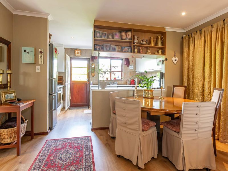Open plan dining area featuring laminate flooring and a kitchen pass-through with built-in shelving, connecting to a functional kitchen space.