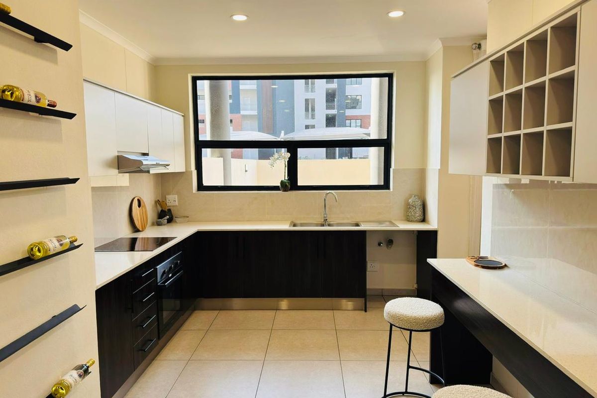 Modern kitchen featuring dark cabinetry, light countertops, integrated hob and oven, extractor fan, and a breakfast nook with built-in shelving.