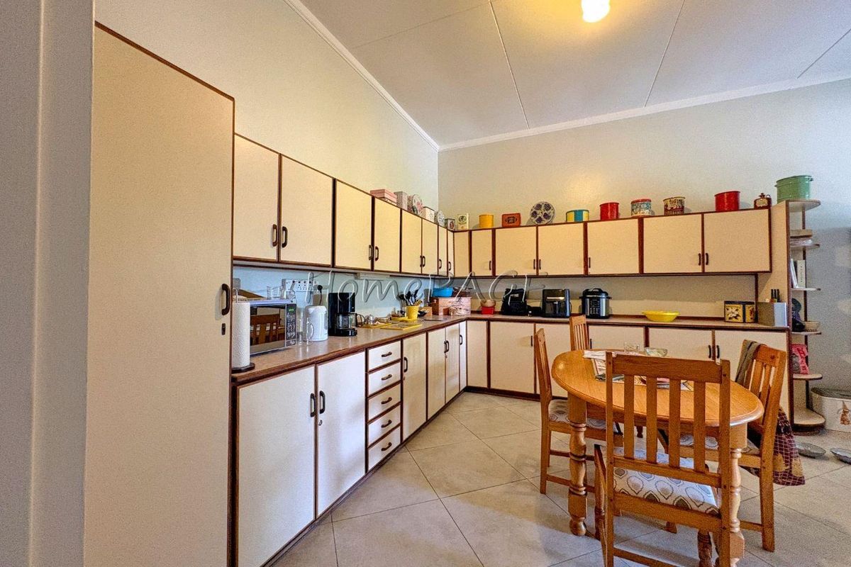 A functional kitchen featuring extensive laminate cabinetry, tiled flooring, and ample counter space, offering a practical layout for daily meal preparation.