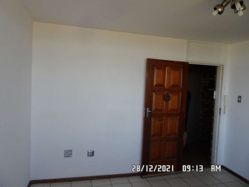 An empty entrance area featuring tiled flooring, a solid timber panelled door, and an integrated intercom system.