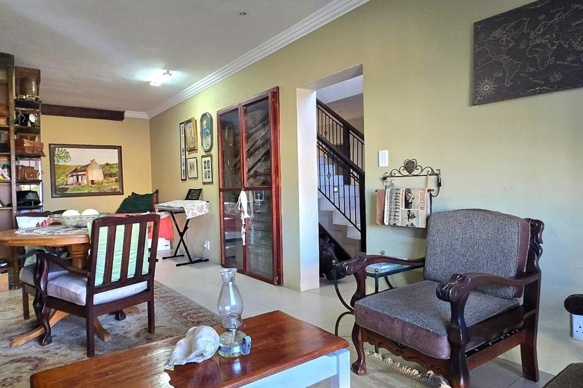 Spacious living area featuring built-in floor-to-ceiling wooden shelving, tiled flooring, and a glass-paneled door leading to an internal staircase.