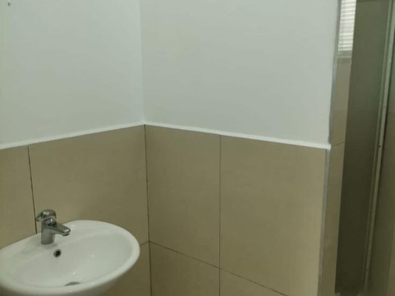 A clean, modern bathroom featuring a pedestal basin with a mixer tap, tiled walls, and a glass-enclosed shower area.