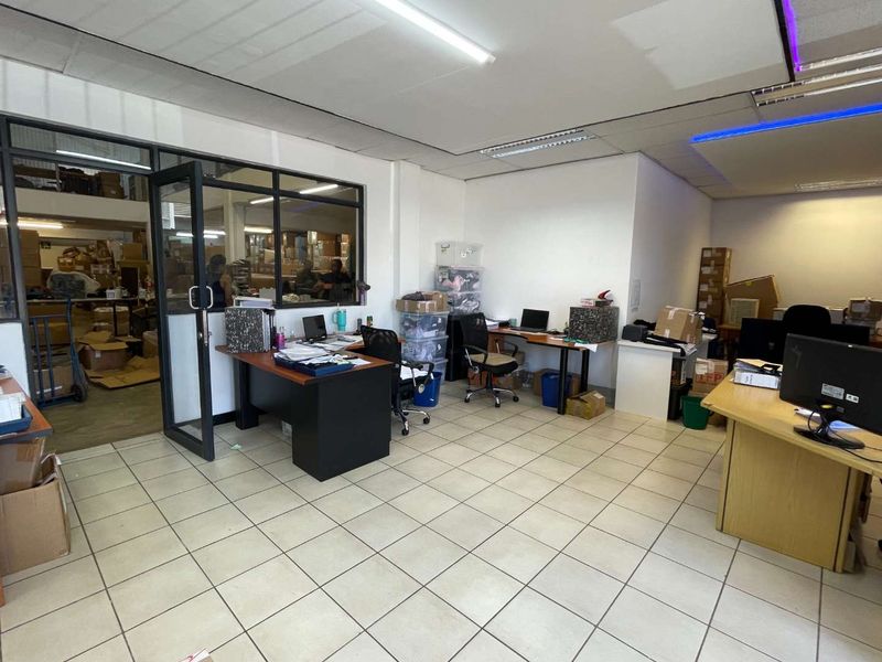 Functional office space featuring tiled flooring, a glass partition wall, and integrated fluorescent lighting, suitable for a professional work environment.