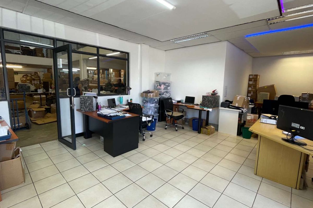 Functional office space featuring tiled flooring, a glass partition wall, and integrated fluorescent lighting, suitable for a professional work environment.