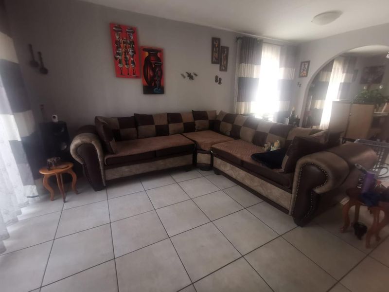 A living room featuring neutral ceramic floor tiles and an arched doorway leading to an adjacent space, providing a functional and open layout.