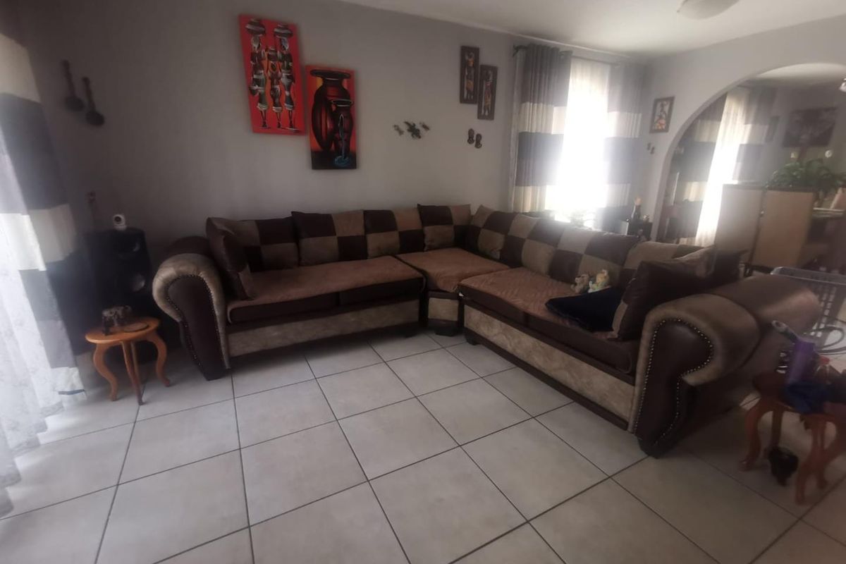 A living room featuring neutral ceramic floor tiles and an arched doorway leading to an adjacent space, providing a functional and open layout.