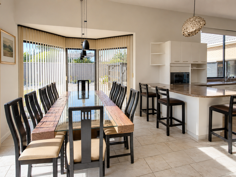 Spacious open-plan kitchen and dining area featuring granite countertops, a breakfast bar, tiled flooring, and large sliding doors providing ample natural light.
