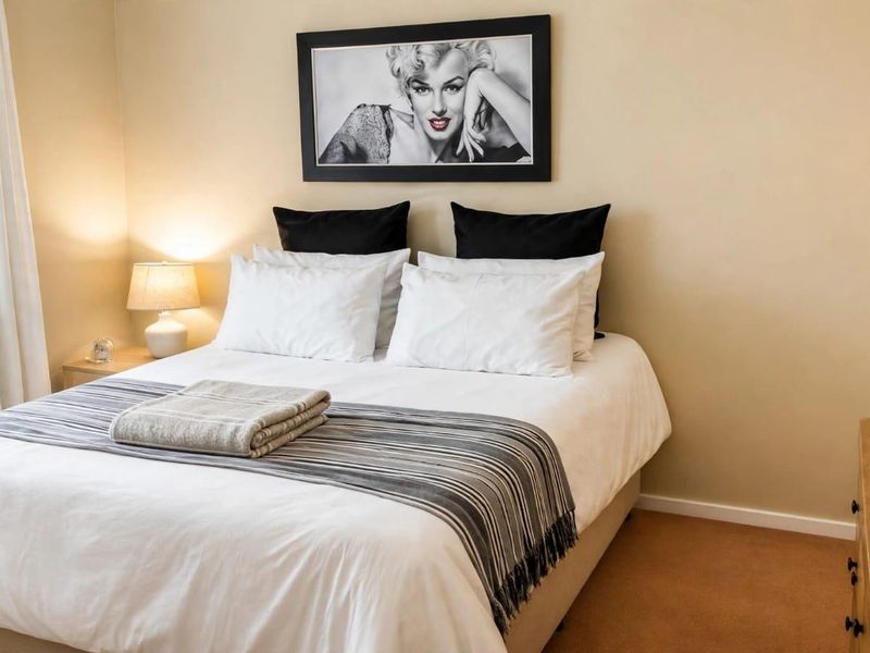 A well-maintained bedroom featuring neutral wall tones and carpeted flooring, providing a comfortable and functional sleeping space.