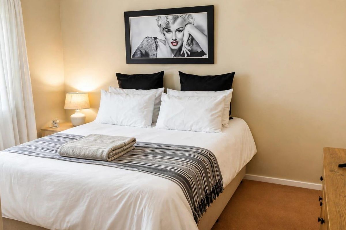 A well-maintained bedroom featuring neutral wall tones and carpeted flooring, providing a comfortable and functional sleeping space.
