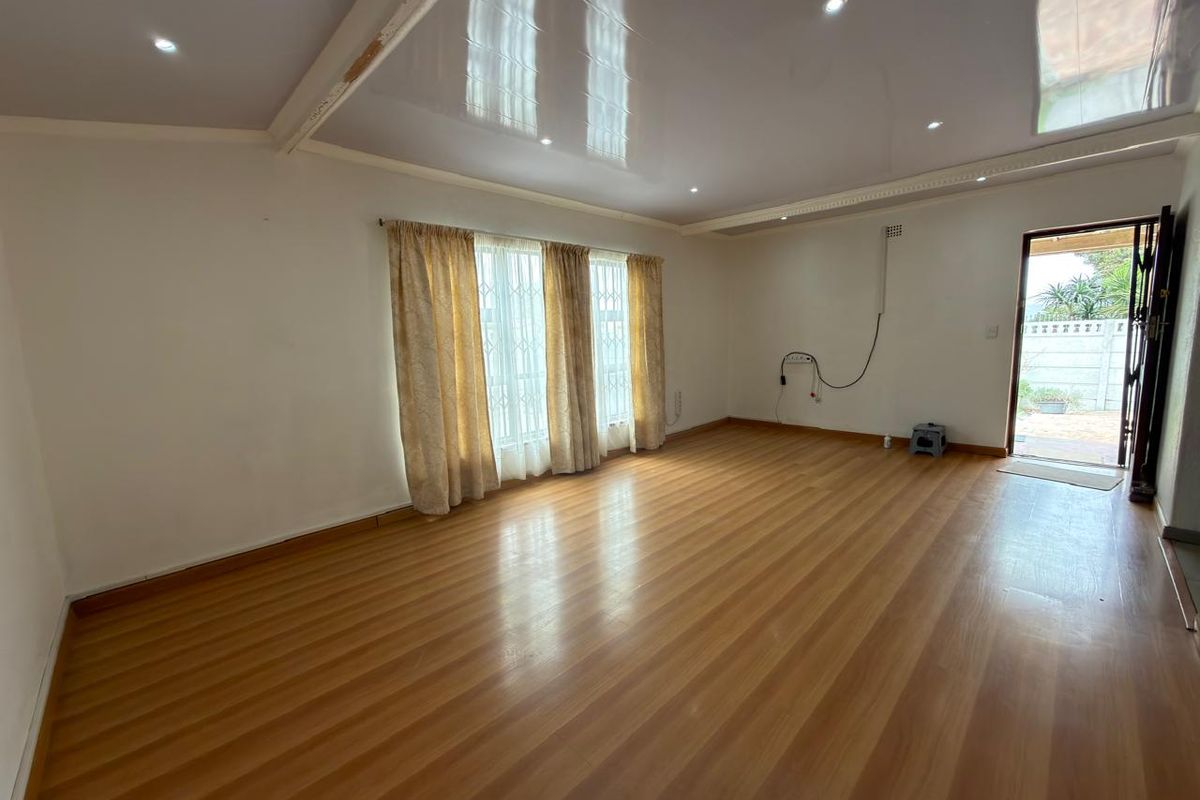 Spacious, empty living area featuring laminate flooring, recessed downlighting, and direct access to the exterior through a security gate.