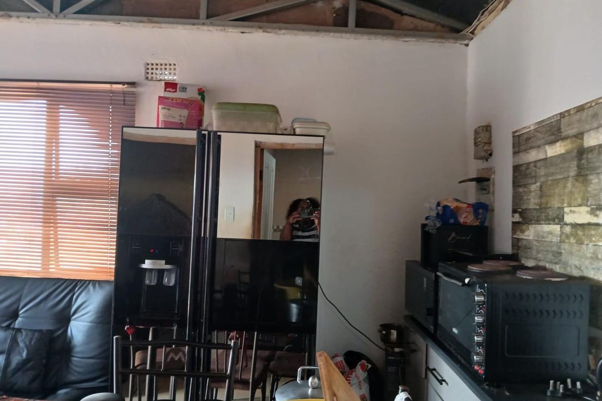 A kitchen area featuring exposed roof trusses and basic cabinetry, currently requiring significant renovation to finish the ceiling and wall surfaces.
