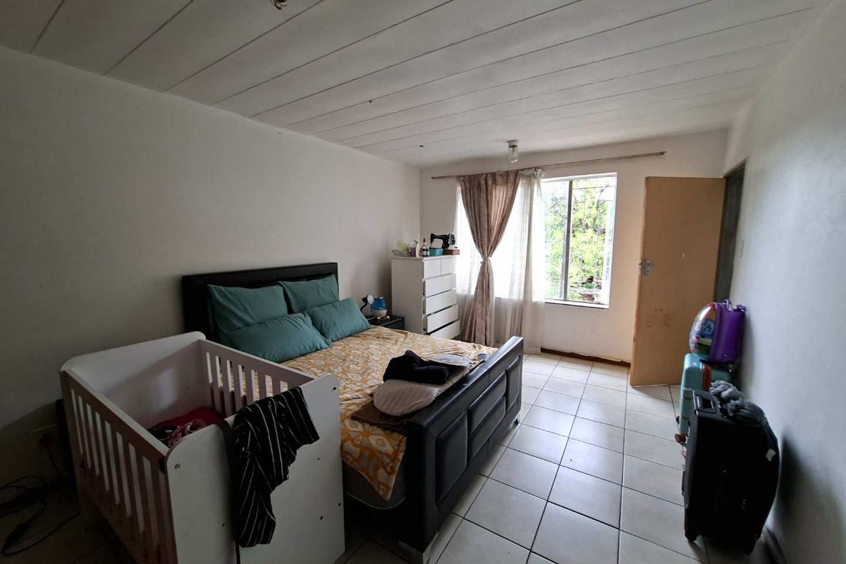 A bedroom featuring tiled flooring, a window with curtain rails, and a standard interior door.