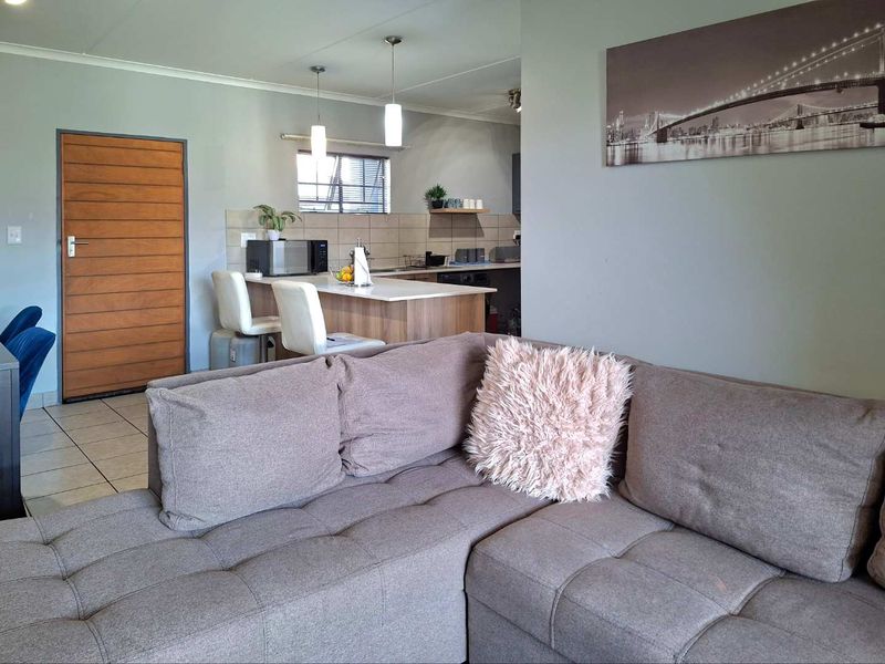 Open plan living area featuring a kitchen with a breakfast island, tiled flooring, and neutral wall finishes, creating a functional and connected living space.