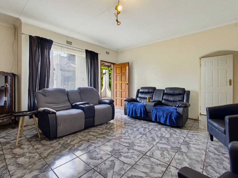A living room featuring tiled flooring, coved ceilings, and direct access to an outdoor area through a timber door.