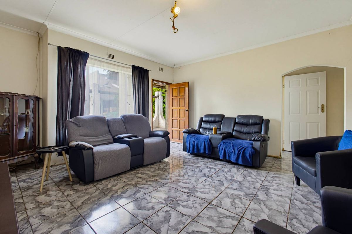 A living room featuring tiled flooring, coved ceilings, and direct access to an outdoor area through a timber door.