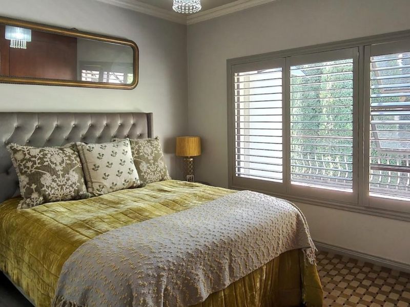 A well-maintained bedroom featuring plantation shutters, crown molding, and a built-in wardrobe, offering a comfortable and finished living space.